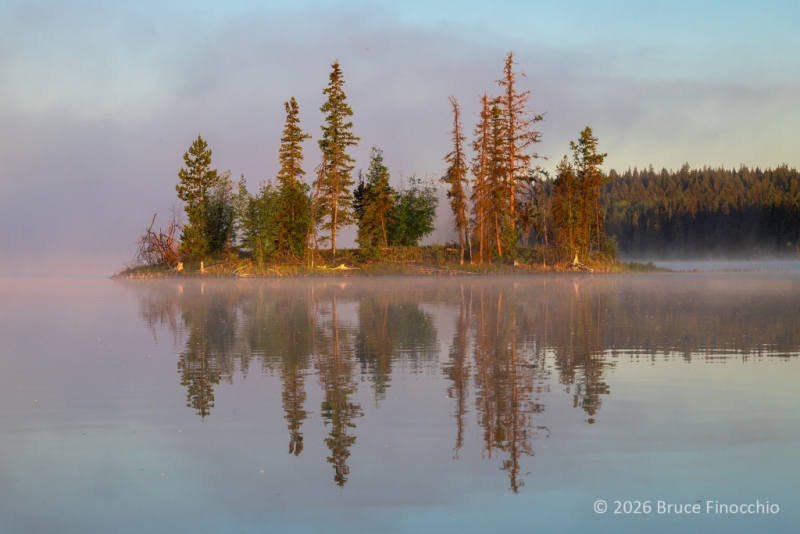 Small Island On A British Columbia Lake Illuminated By Rising Sunshine